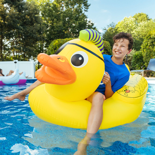 Child sitting on the punk duck holding on to the handles on the head